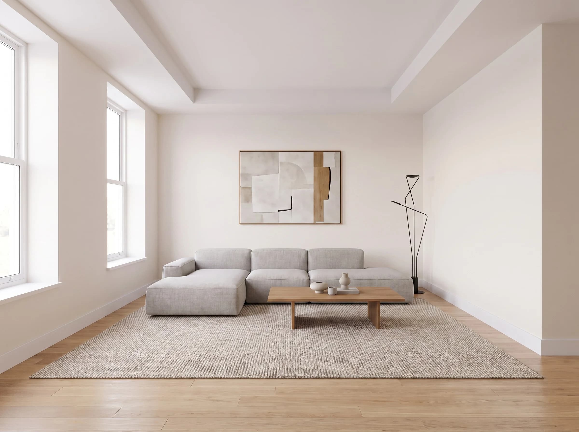 Espacio abierto amueblado en estilo moderno con un sofá seccional gris, una mesa de centro baja de madera, un tapete texturizado y arte abstracto